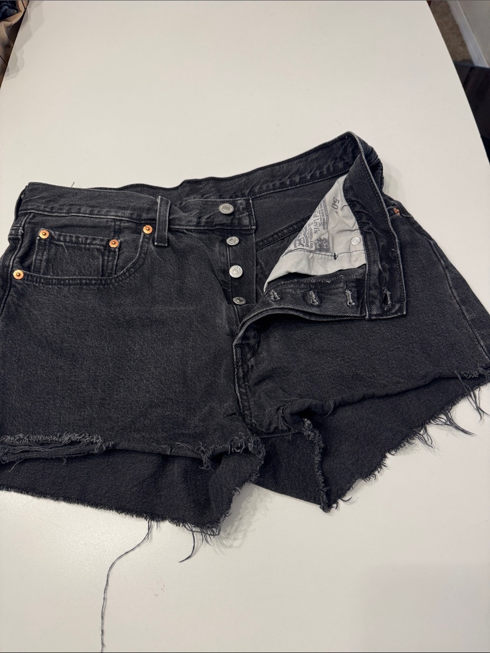Vintage 90s Levi’s 501 button fly raw hem faded black denim jean shorts size 30